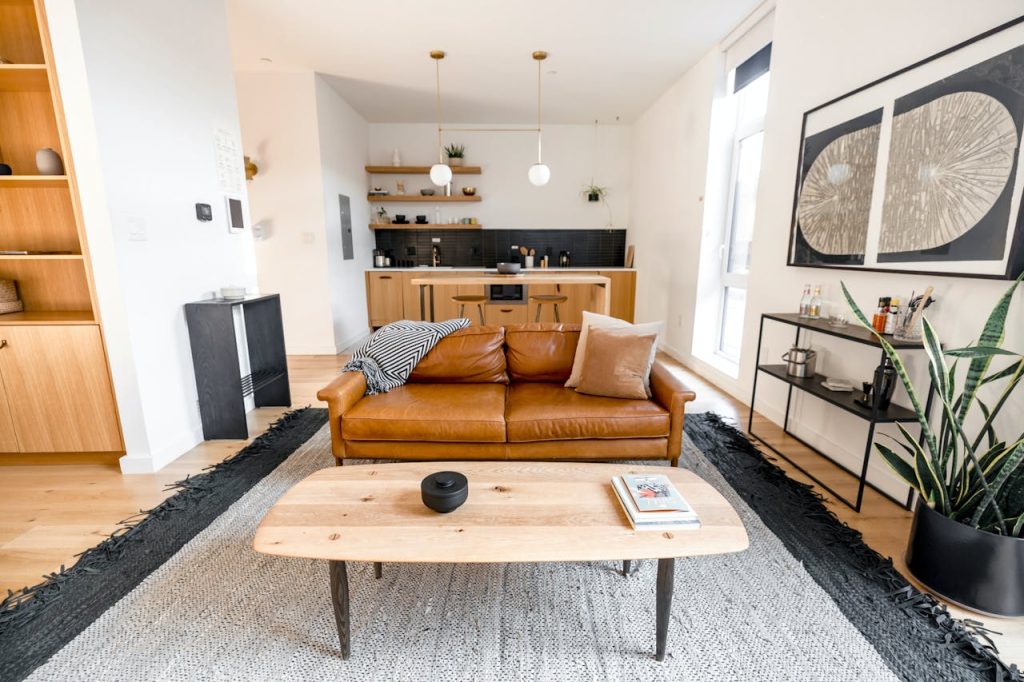 brown-wooden-table-near-brown-couch-12931939 Stylish modern living room with a leather sofa, kitchen area, and decor elements.
